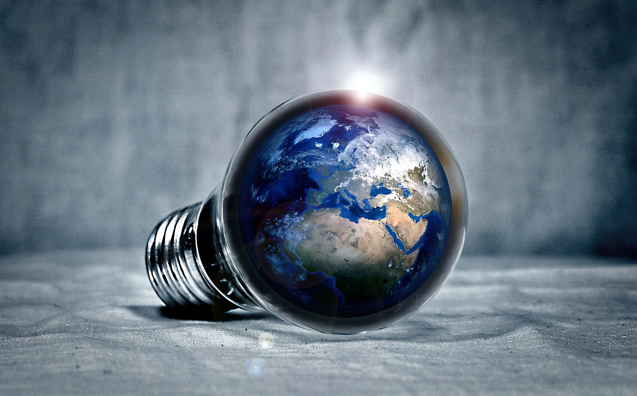 Une ampoule dans laquelle se reflète le globe terrestre pour illustrer la problématique de l'énergie et du changement climatique